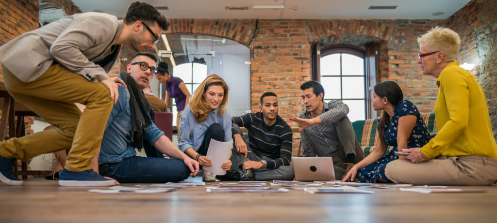 Branding agency employees seated on the floor of an agency building brainstorming