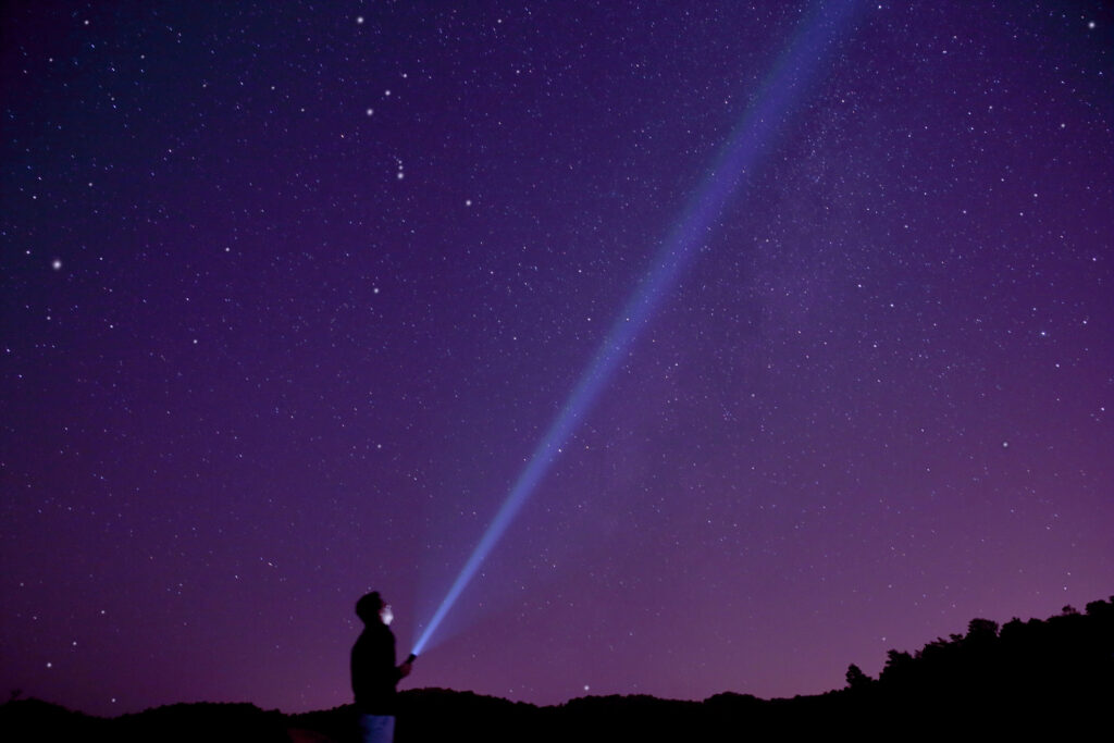 Image representing how Clear Aim will help you craft a brand strategy for your business. Photo shows a long exposure of stars with a ray of light shining toward a point in the distance.